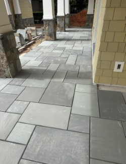 Thermal pattern bluestone patio in a random ashlar layout beside a porch