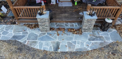 Broken flagstone walkway leading to a deck entrance flanked by stone pillars