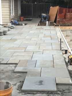 Bluestone pattern flagging patio under installation on a screed bed